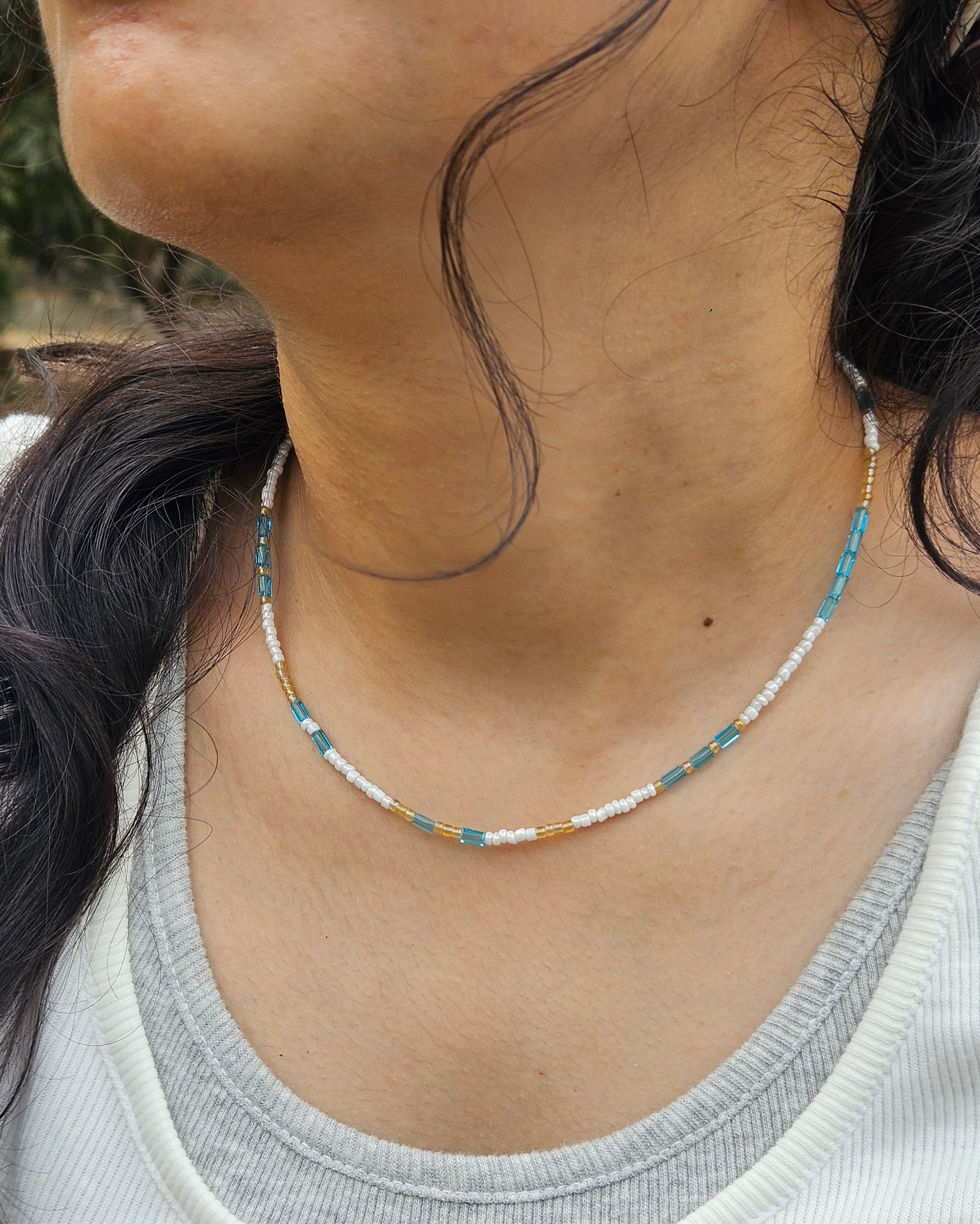 Close-up of a person wearing a necklace with a natural outdoor background