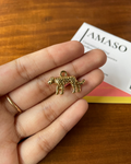 Gold leopard charm held in a hand with a wooden surface and AMASO box in the background