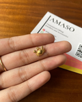 Gold crab-shaped earring on a finger with AMASO branding in the background