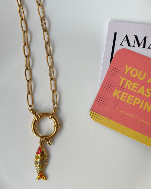 Gold necklace on a white plate with a magazine underneath