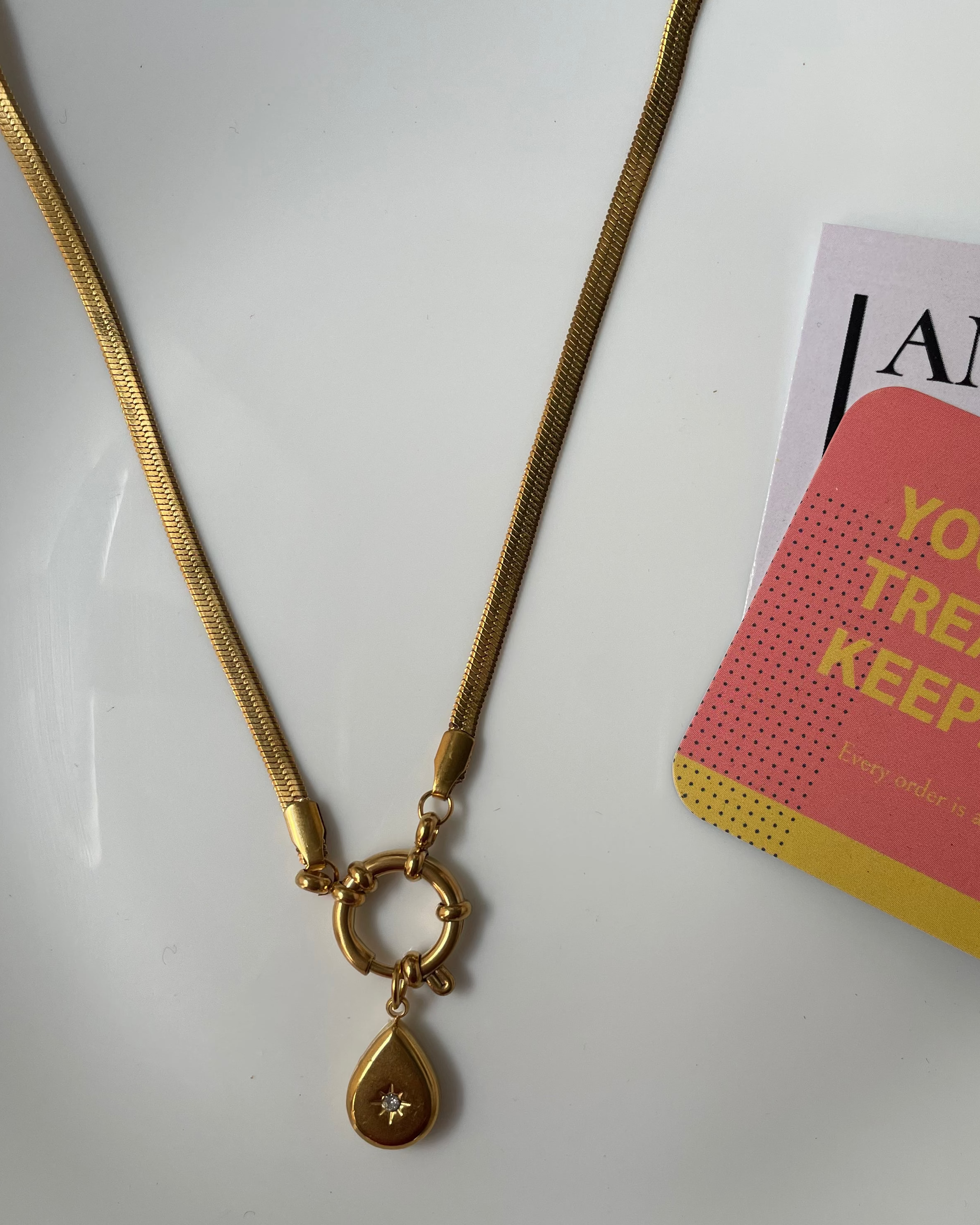 Gold necklace on a white surface with a card reading 'You are a treasure worth keeping' by Amazon.
