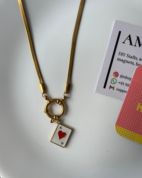 Gold necklace with a heart-shaped card pendant on a white surface
