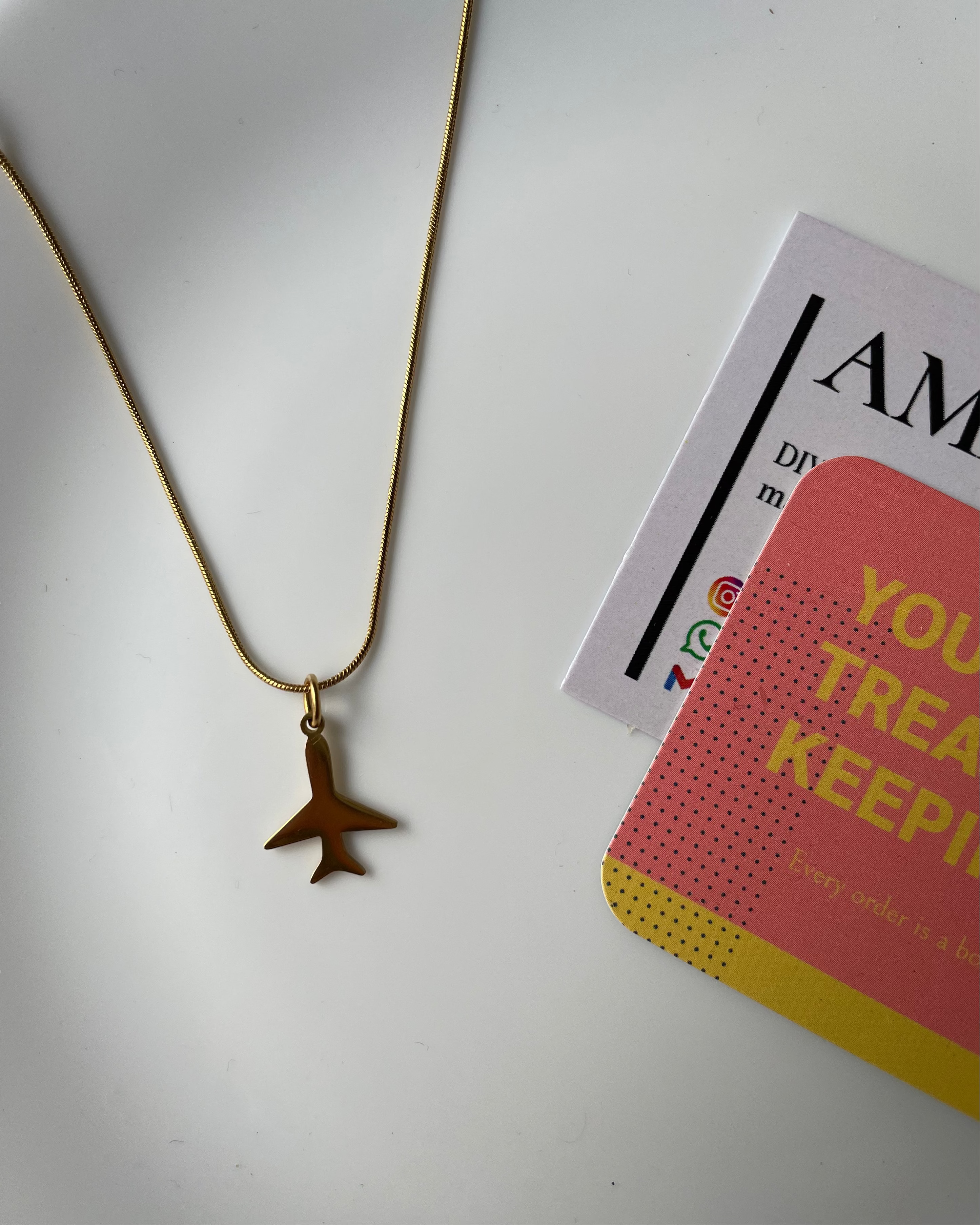 Gold necklace with a star pendant on a white surface with a card in the background.