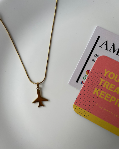 Gold necklace with a star pendant on a white surface with a card in the background.