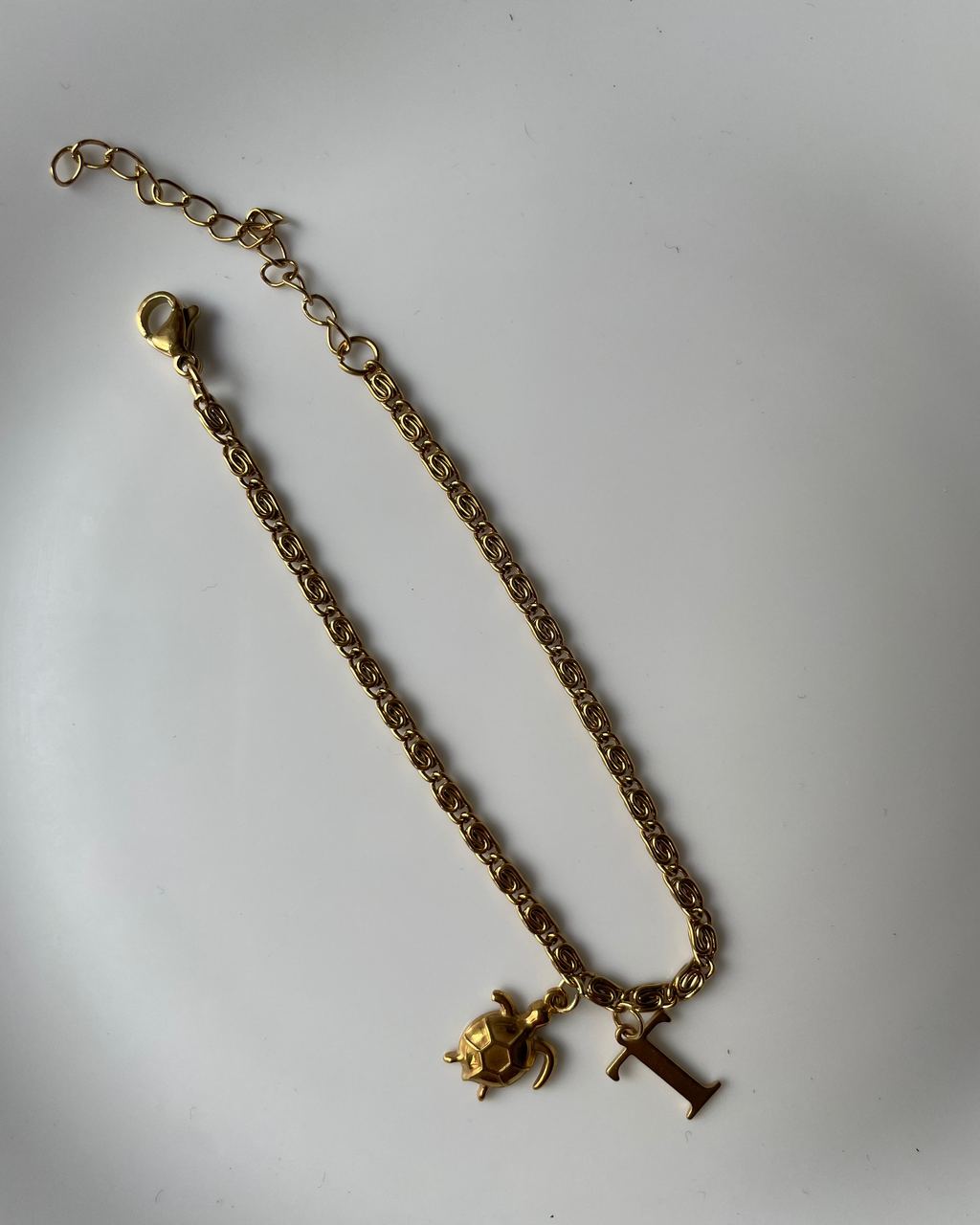 Gold chain bracelet with charms on a white background