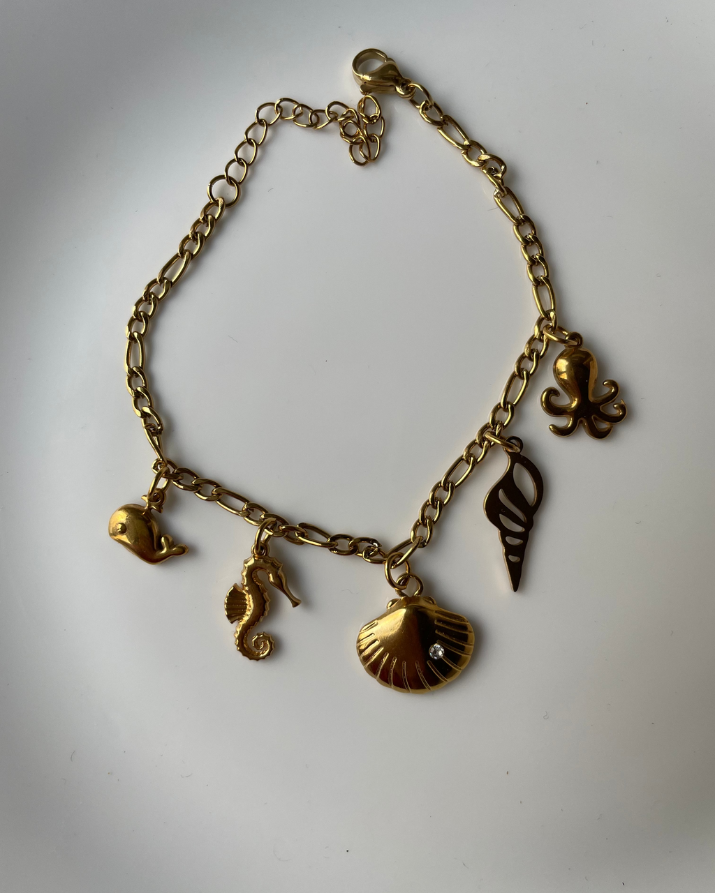 Gold bracelet with various charms on a white background
