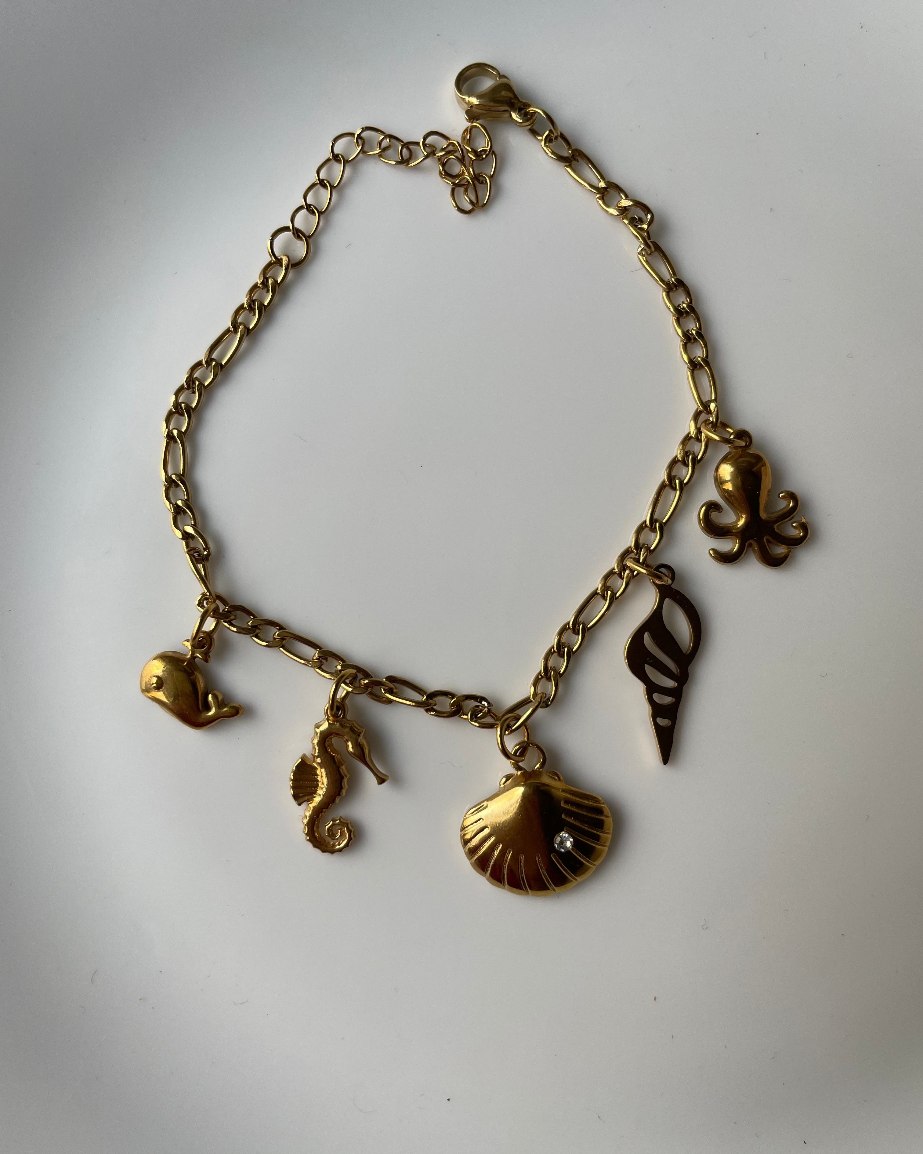 Gold bracelet with various charms on a white background