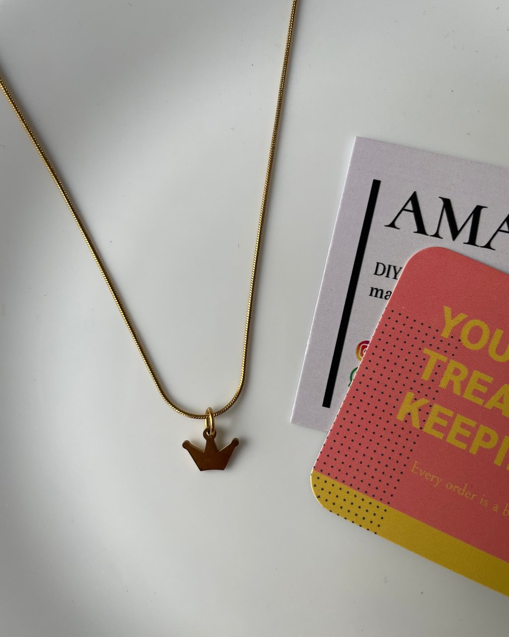 Gold necklace on a white surface with a magazine in the background