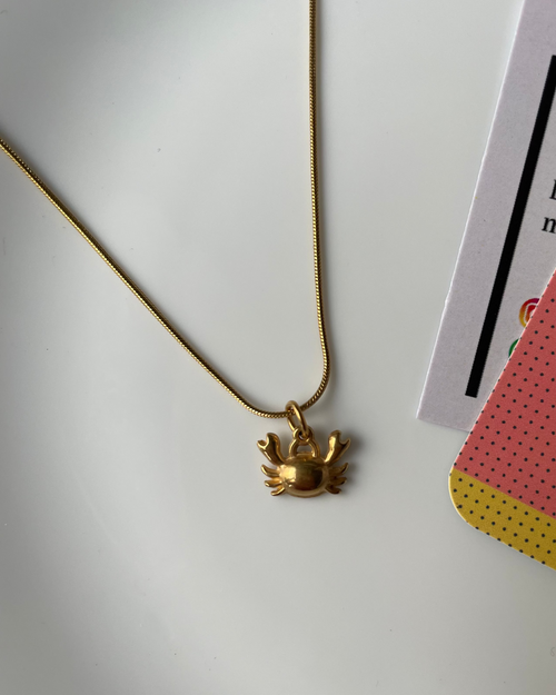 Gold necklace with a floral pendant on a white surface