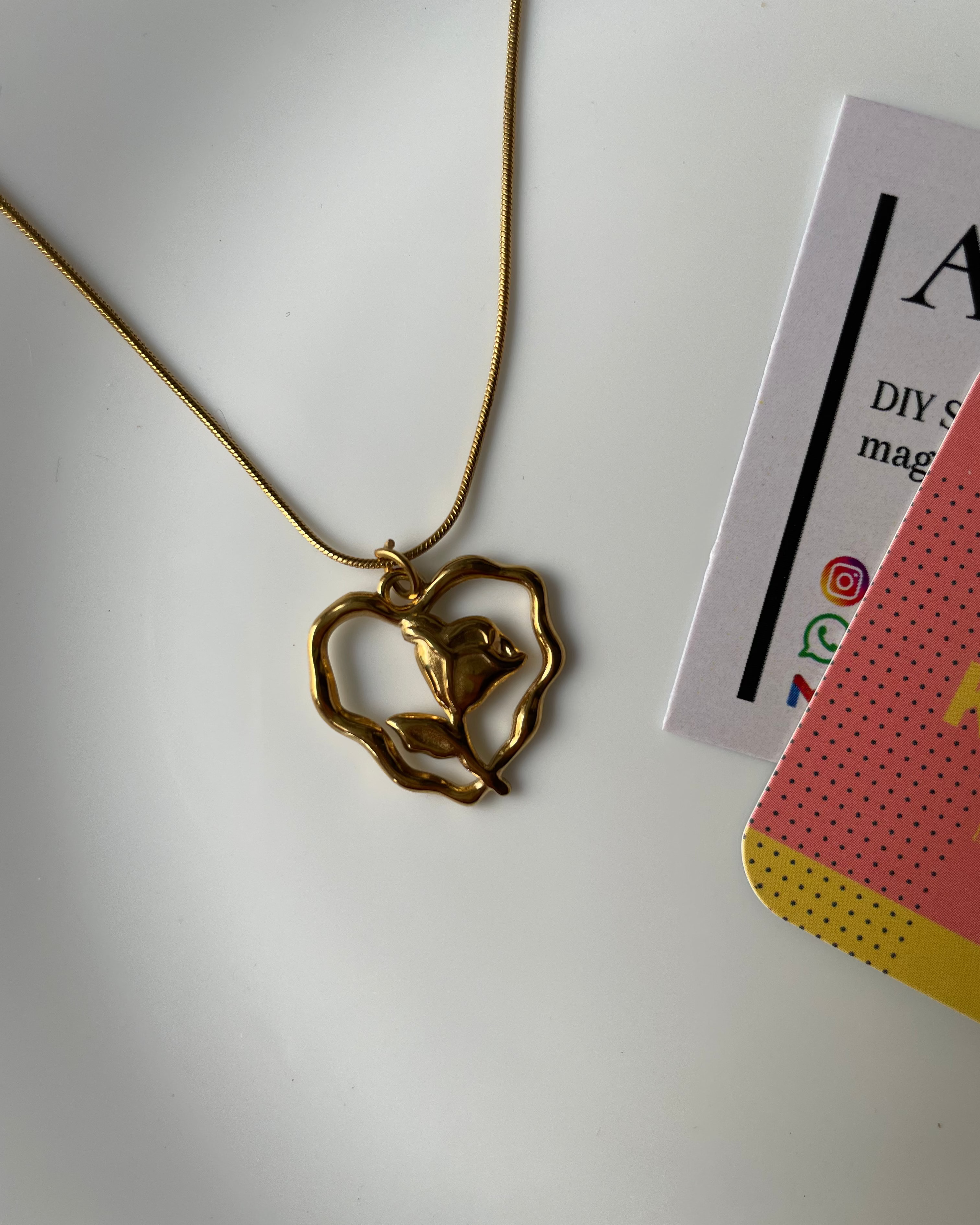Gold necklace with a rose-shaped pendant on a white background