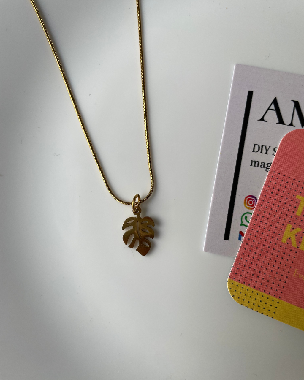 Gold leaf-shaped bookmark on a white surface with a magazine in the background