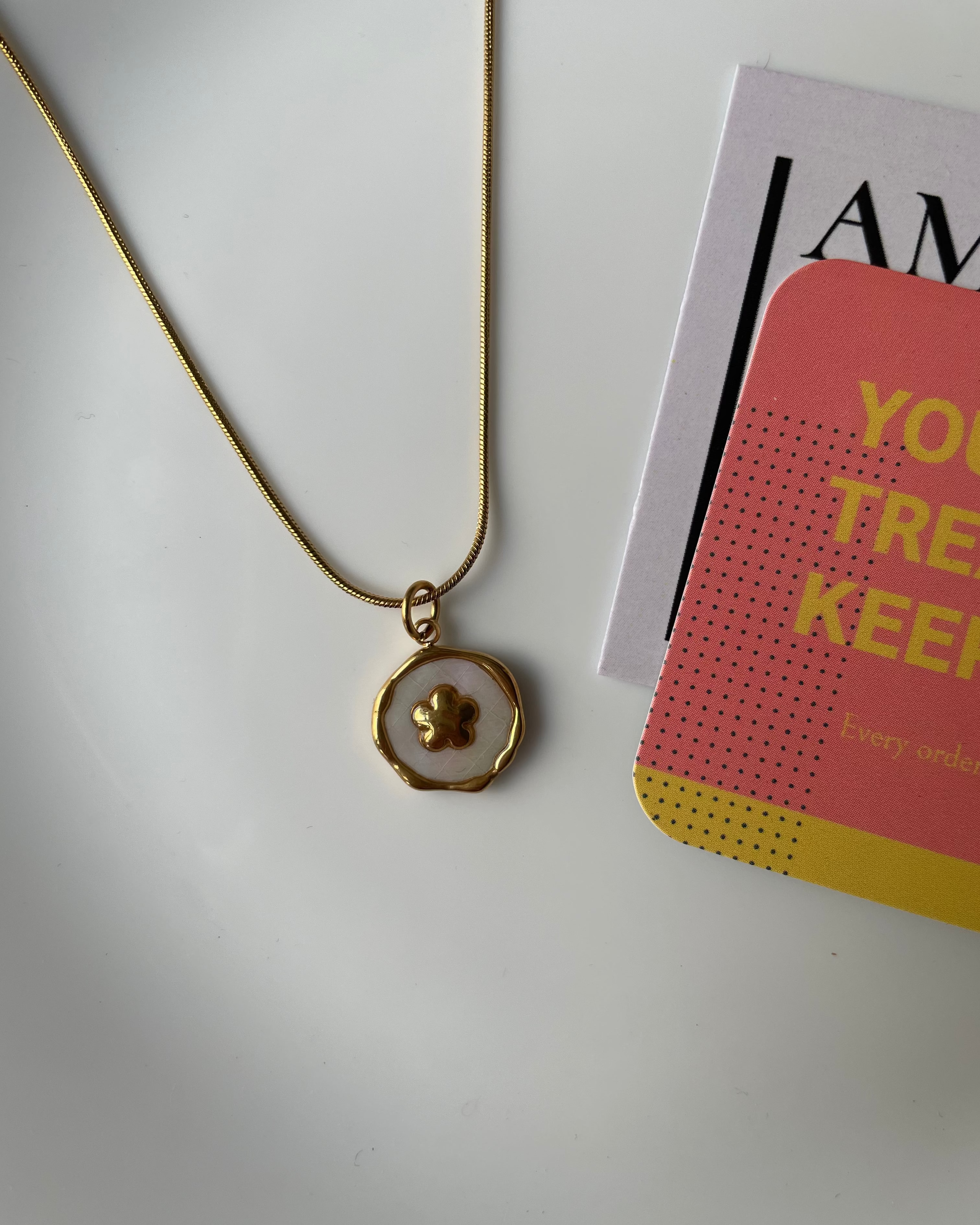 Gold necklace with a pendant on a white surface
