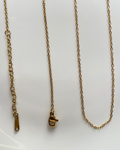 A gold-toned metal chain necklace with a lobster clasp and adjustable sliding ring extender, laid out on a plain white surface.
