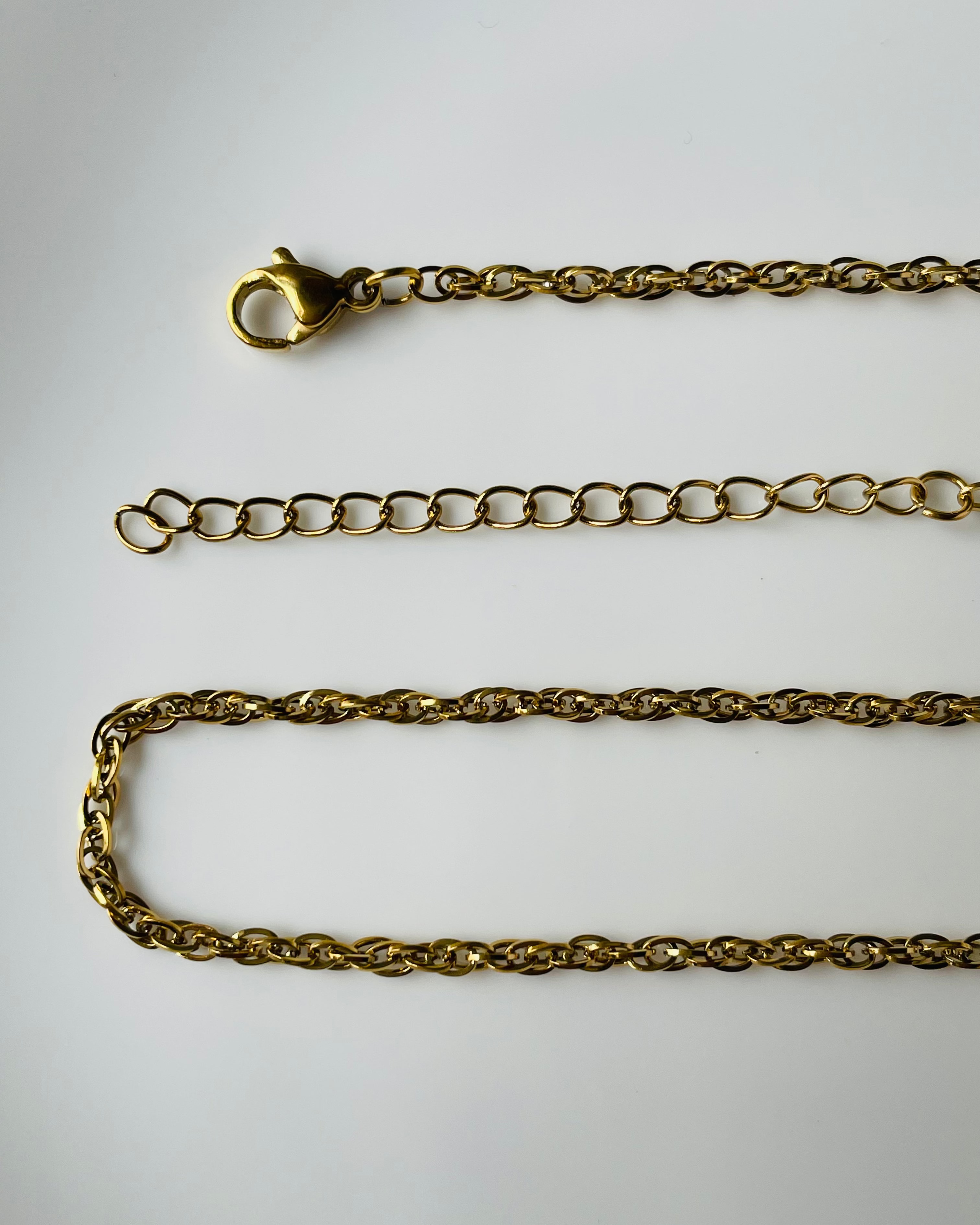 A gold-toned metal chain necklace with a lobster clasp, shown laid out on a plain white background.
