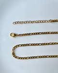 A gold Figaro chain necklace with a lobster clasp, laid out on a plain white surface.